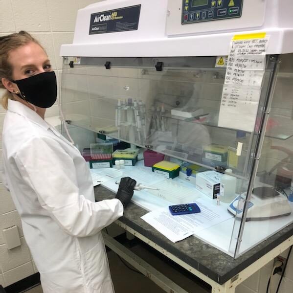 Jordyn in front of fume hood holding pipette