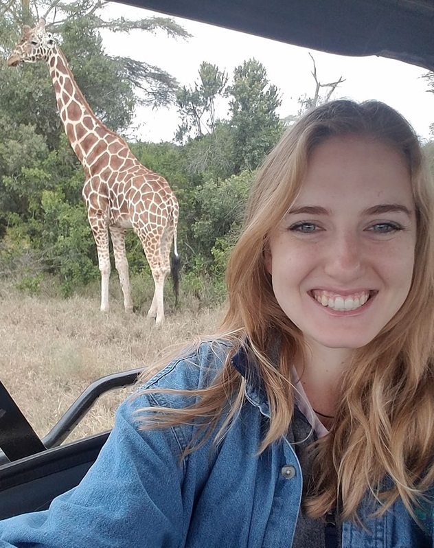 Jordyn Chase in a vehicle with giraffe behind her