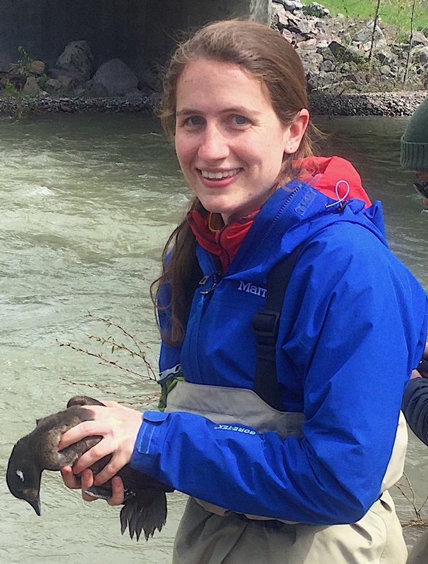 Sarah Gaulke holding a bird in a stream