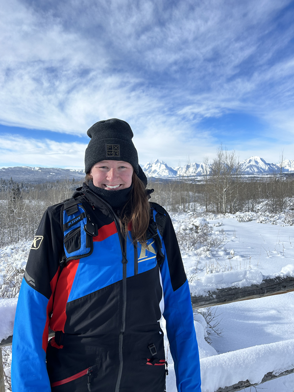 Angela Huss in winter gear in front of snowy mountain scene